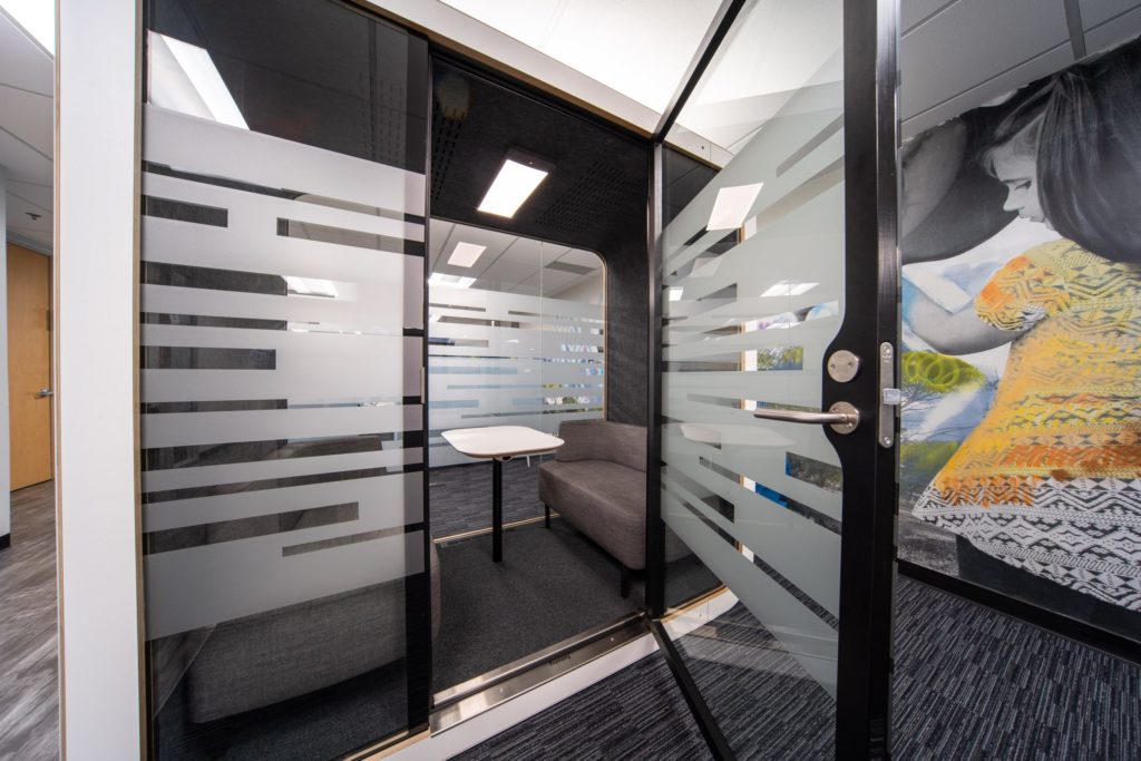 Privacy pod with frosted glass walls in an office.