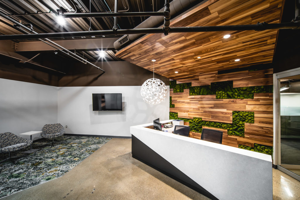 An office reception area with wood panels and live plants in the wall.