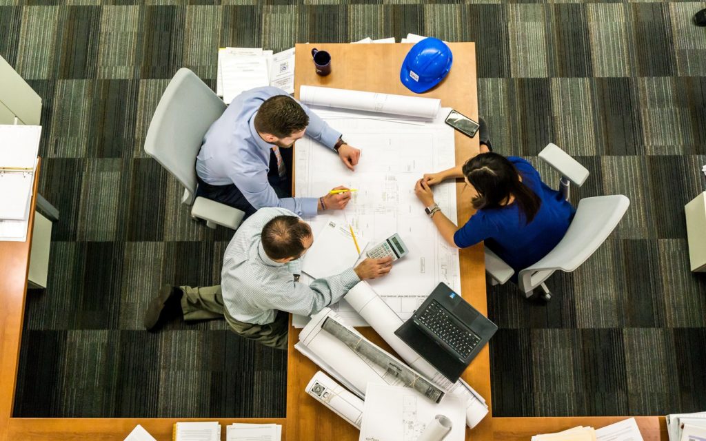 Overhead view of people looking at design plans at a desk.