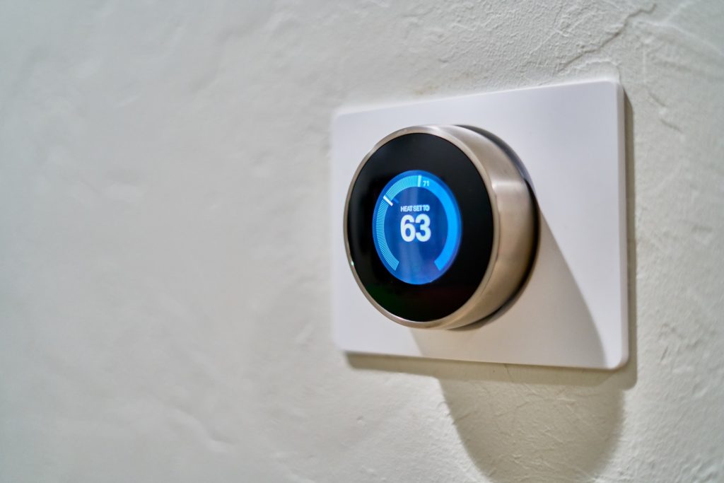 A smart thermostat installed on a white wall.