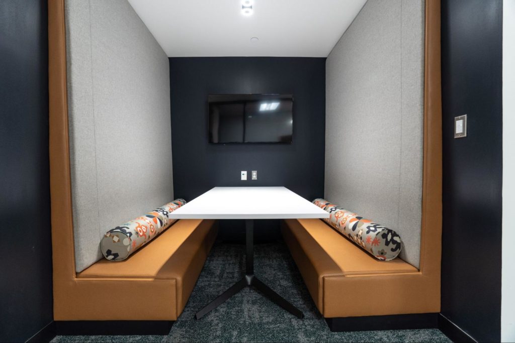 A secluded meeting area in an office with a video monitor on the wall.